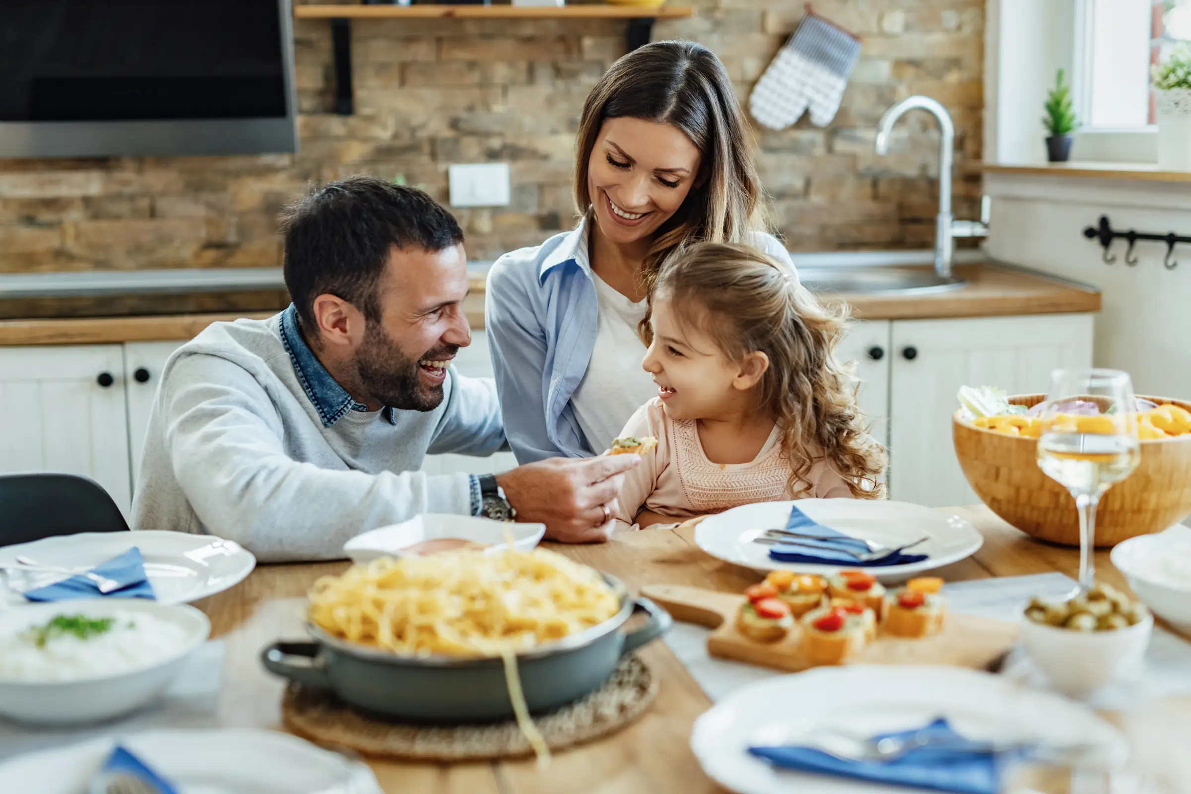 Familia riendo alrededor de la mesa durante un almuerzo de pasta en casa