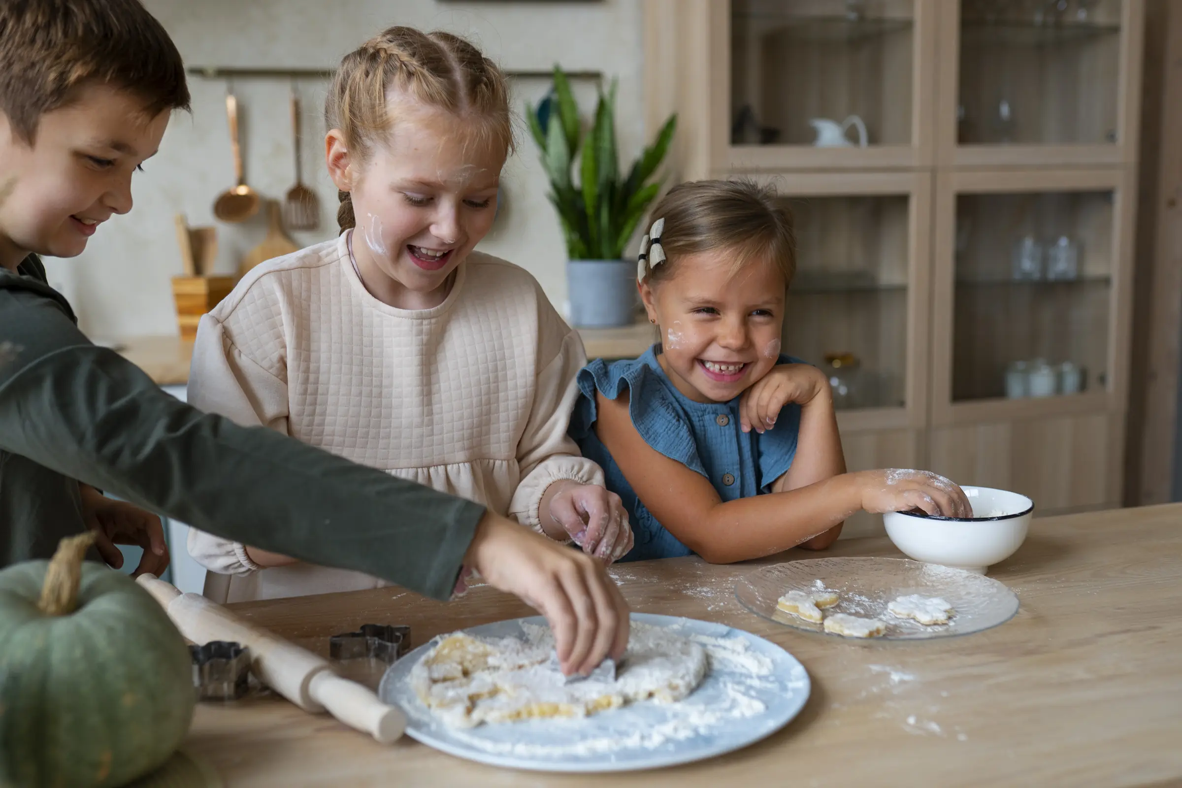 Tres niños riendo mientras preparan pasta casera en la cocina